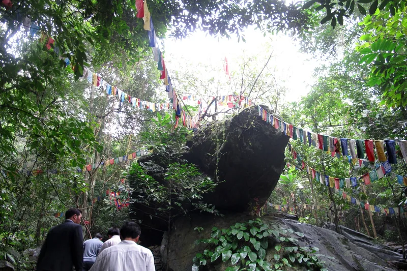 Du khách đi bộ dưới những dải cờ phướn rực rỡ gần tảng đá lớn trong rừng ở Tây Thiên, Tam Đảo.