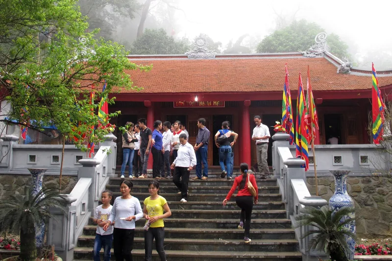 Du khách leo bậc thang đá lên ngôi đền mái đỏ với cờ ngũ sắc ở Tây Thiên, Tam Đảo.