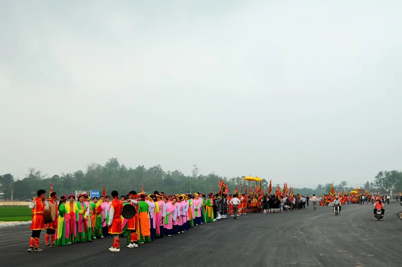 Đoàn rước lễ hội truyền thống với trang phục rực rỡ diễu hành trên con đường ở vùng nông thôn gần Tam Đảo.